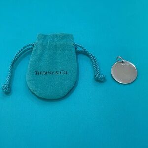 Tiffany & Co. round sterling silver plain tag with jump ring.  Light scratching.